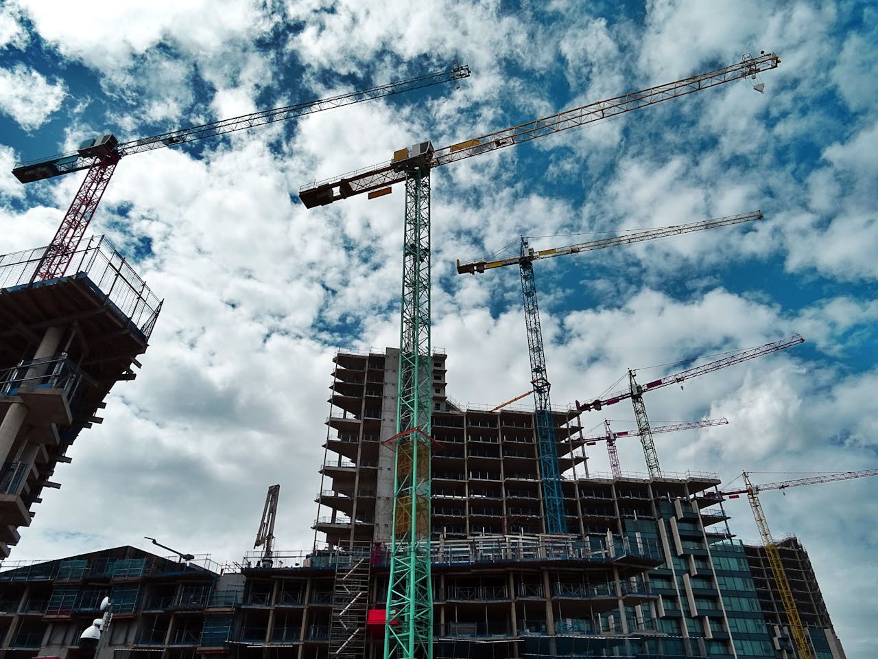about-us Urban construction site with numerous cranes framing rising skyscrapers against a blue sky.